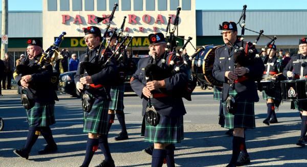 A group of Timmins Police officers in kilts marching down the street.
