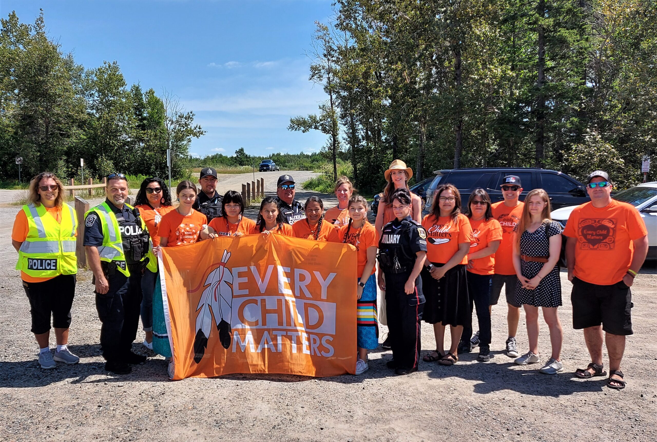 Timmins Police A group of people in orange shirts posing with an orange Timmins Police banner.